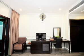 Une chambre d’hôtel équipée d’un bureau, d’une chaise, d’une télévision et d’un ventilateur.