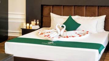 A neatly made bed with a swan-shaped towel arrangement, a green pillow, and a green bedspread.