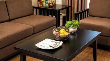 A modern living room with a dark wooden coffee table, a brown sofa, and a small table with snacks and a plant.