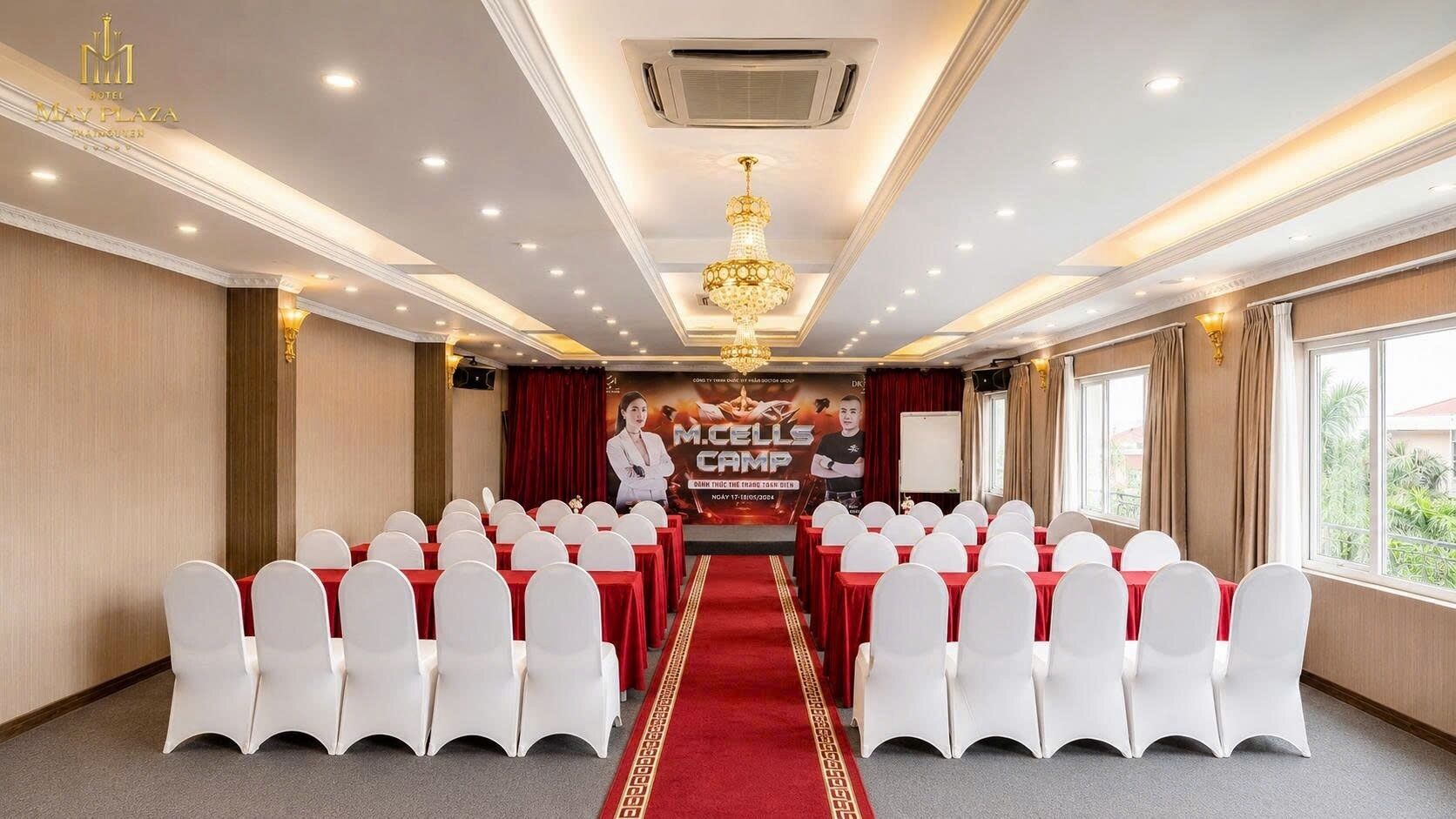 A conference room with rows of white chairs, a podium, and a banner.