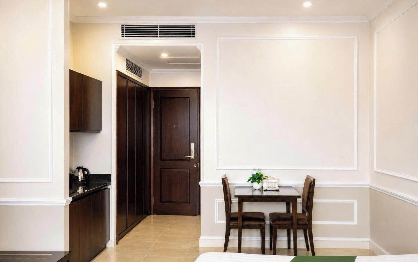 A hotel room with a dining area, a kitchen, and a separate door leading to another room.