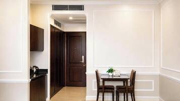 A hotel room with a dining area, a kitchen, and a separate door leading to another room.