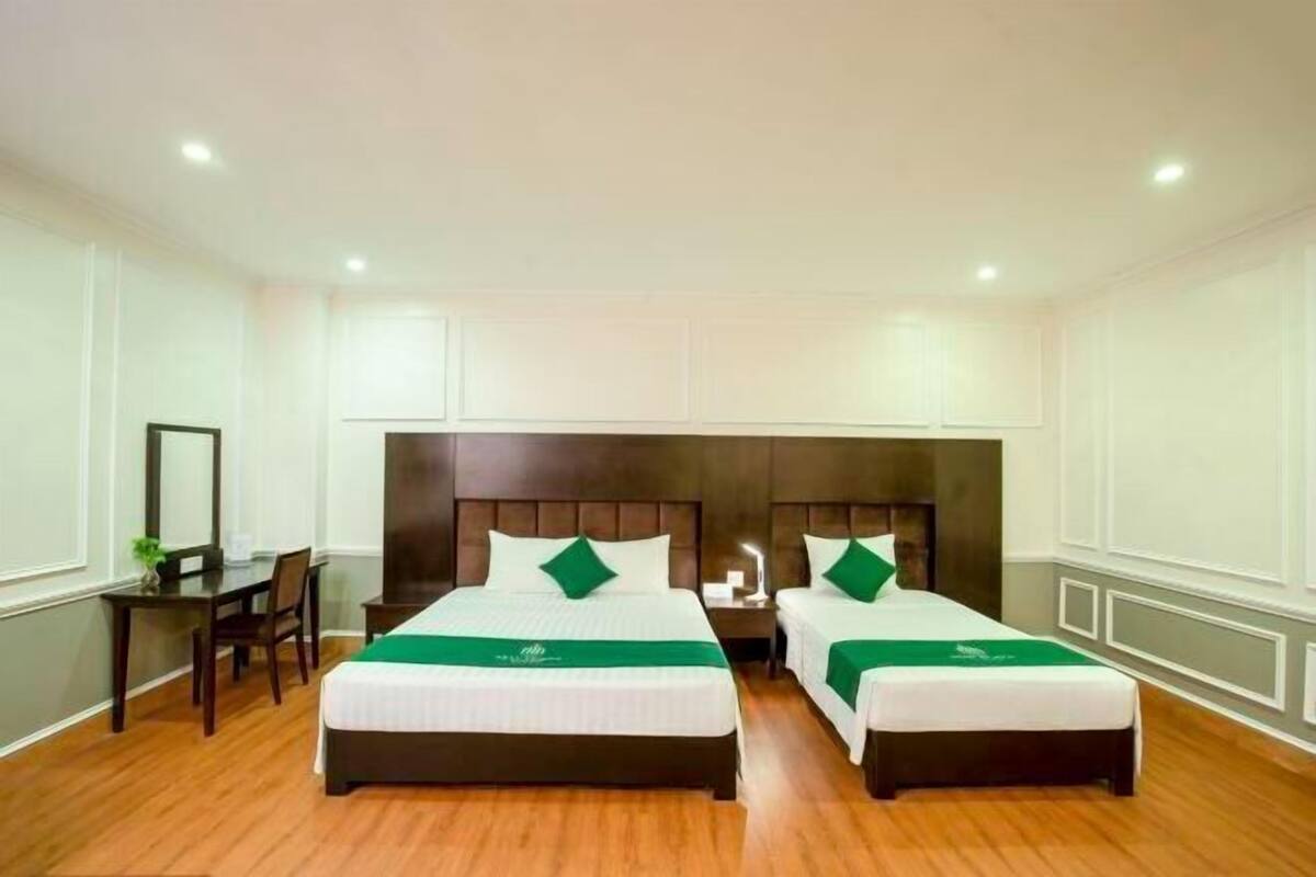 A hotel room with two beds, a desk, and a chair.