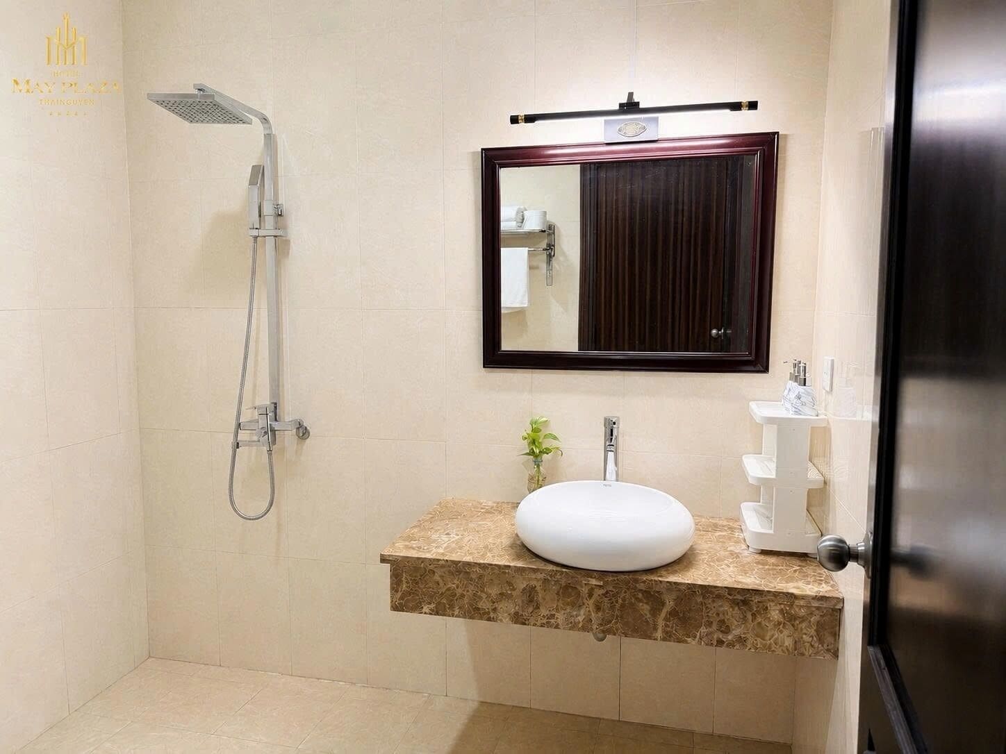 Une salle de bain avec une douche, un lavabo, un miroir et une porte.