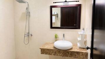 Une salle de bain avec une douche, un lavabo, un miroir et une porte.