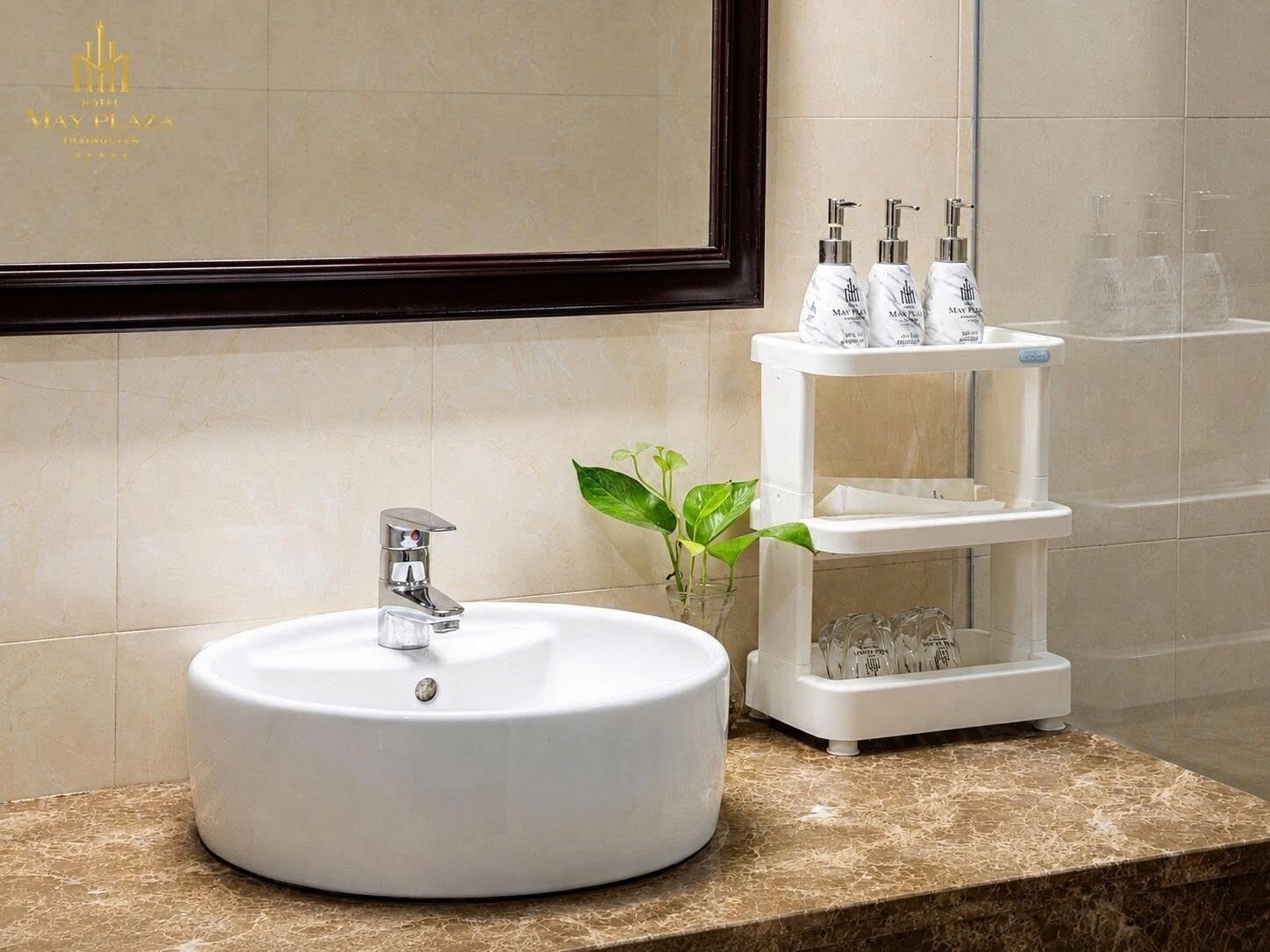 A bathroom with a round white sink, a mirror, and a shelf with toiletries.