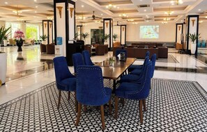 A hotel lobby with a conference table, blue upholstered chairs, and a patterned floor. - May Hotel (Phan Dinh Phung)