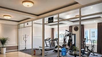 A hotel room with a gym area, including exercise equipment and a water bottle.