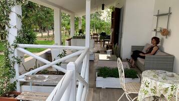 Un área de estar al aire libre techada con mobiliario blanco, una mesa y sillas.