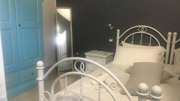A bedroom with a white metal bed frame, a bedside table, a nightstand, and a blue door.