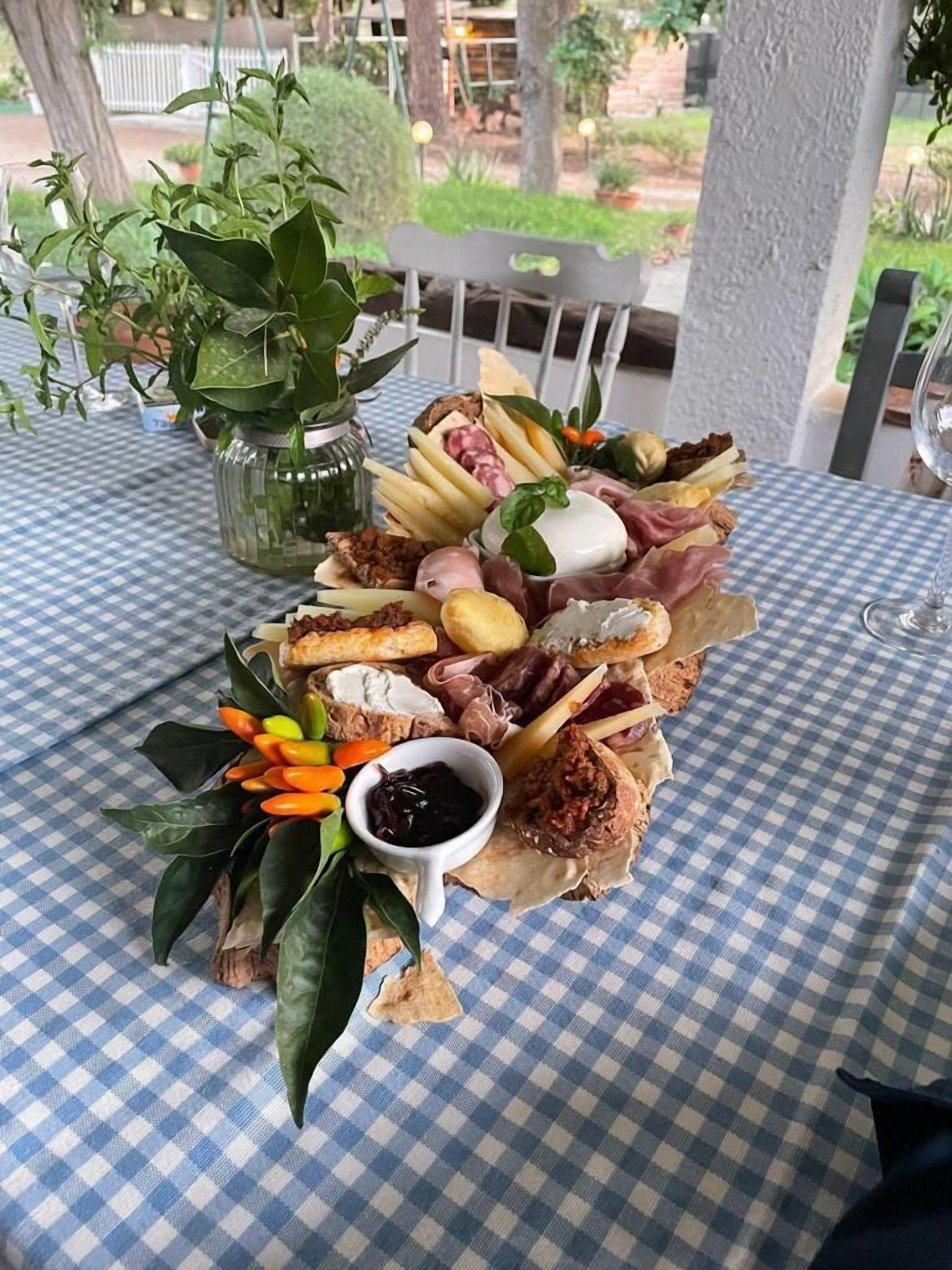Une planche de charcuterie avec divers types de viandes, de fromages et de fruits, le tout disposé sur une nappe à carreaux.