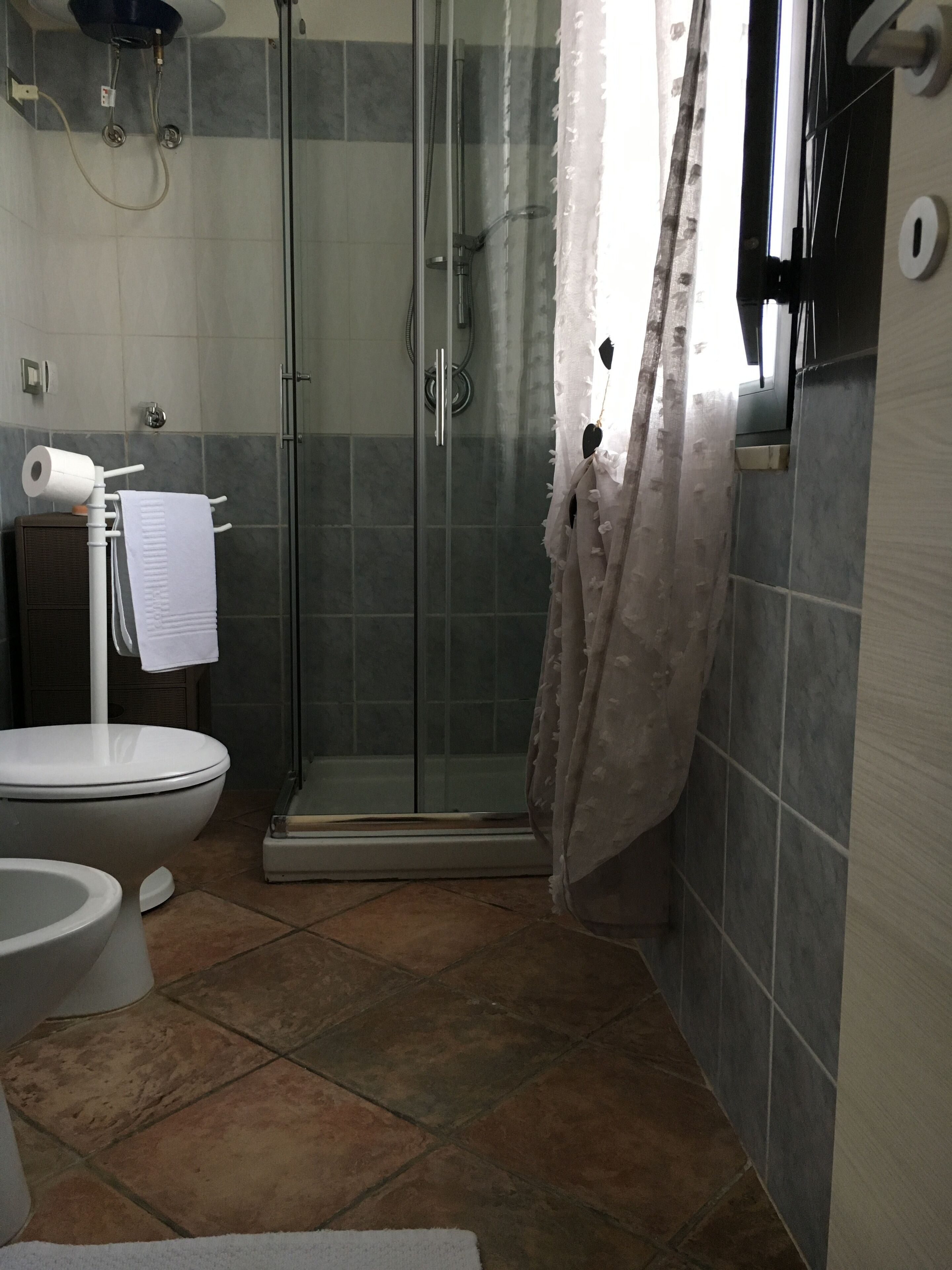 A bathroom with a glass shower enclosure, a toilet, and a sink.