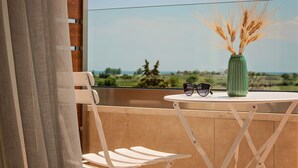 A balcony with a view of the countryside, a green vase with wheat, and a pair of sunglasses on a small table. - Mythic Summer Hotel (Katerini)