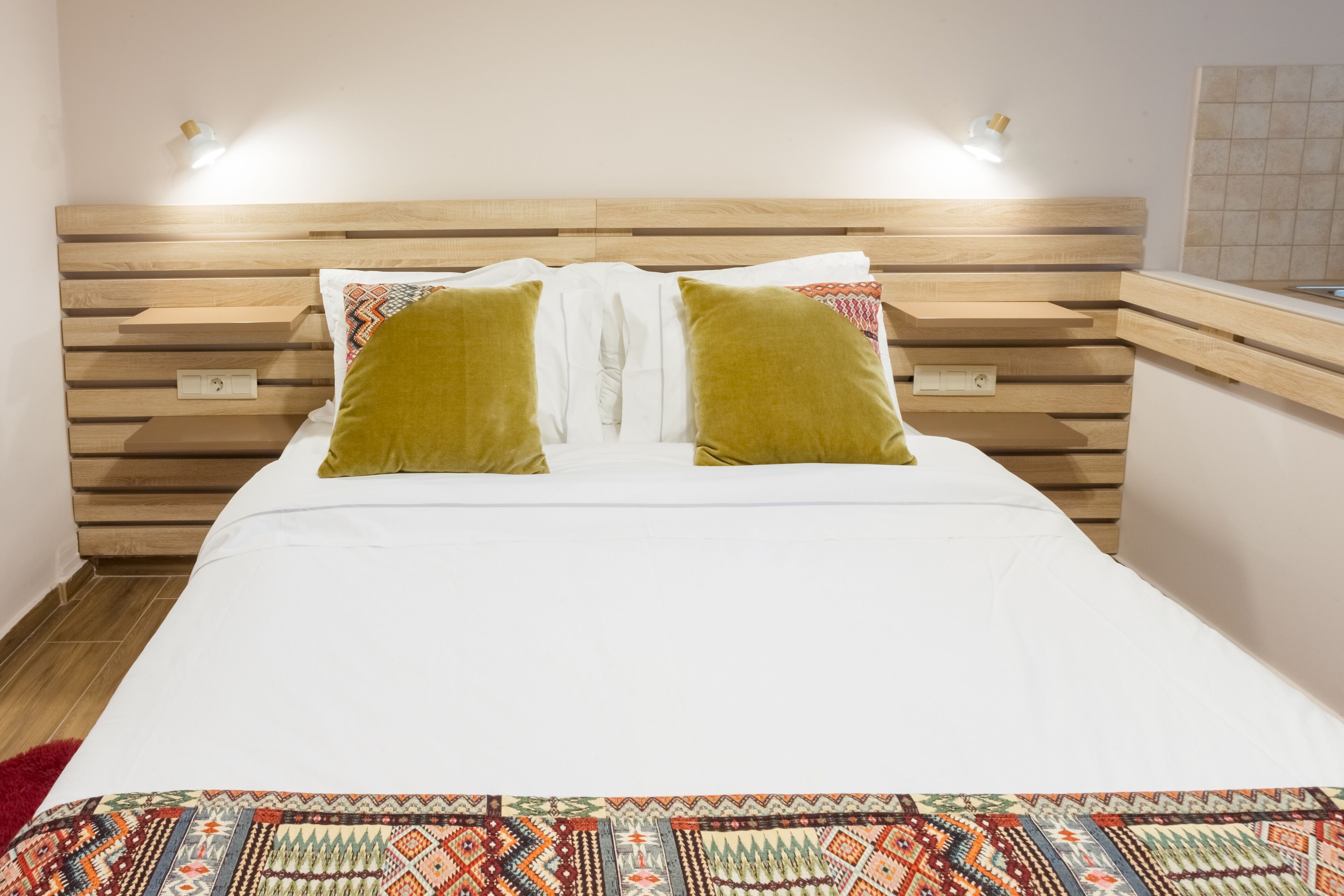 Una cama con cabecera de madera, dos almohadas y un edredón estampado.