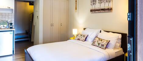 A hotel room with a bed, bedside lamp, and a painting on the wall.
