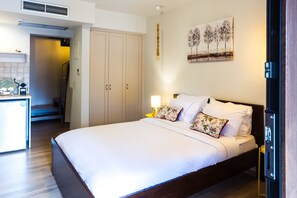 Una habitación de hotel con cama, lámpara de noche y un cuadro en la pared.