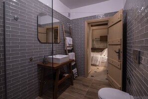 A bathroom with a glass shower enclosure, a wooden vanity with a sink, and a white toilet.