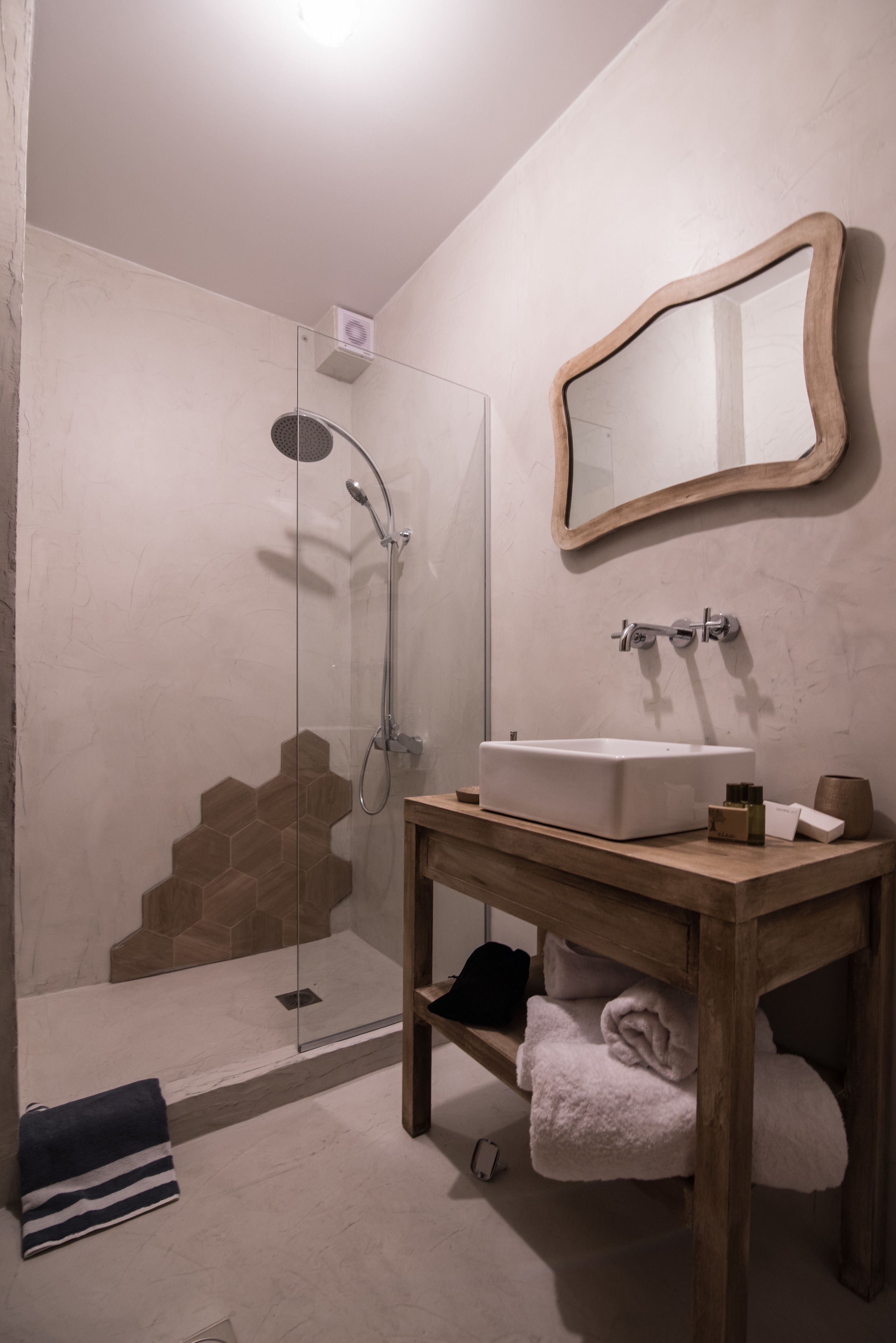 Un bagno con doccia vetrata, un mobile bagno in legno con lavandino e uno specchio.