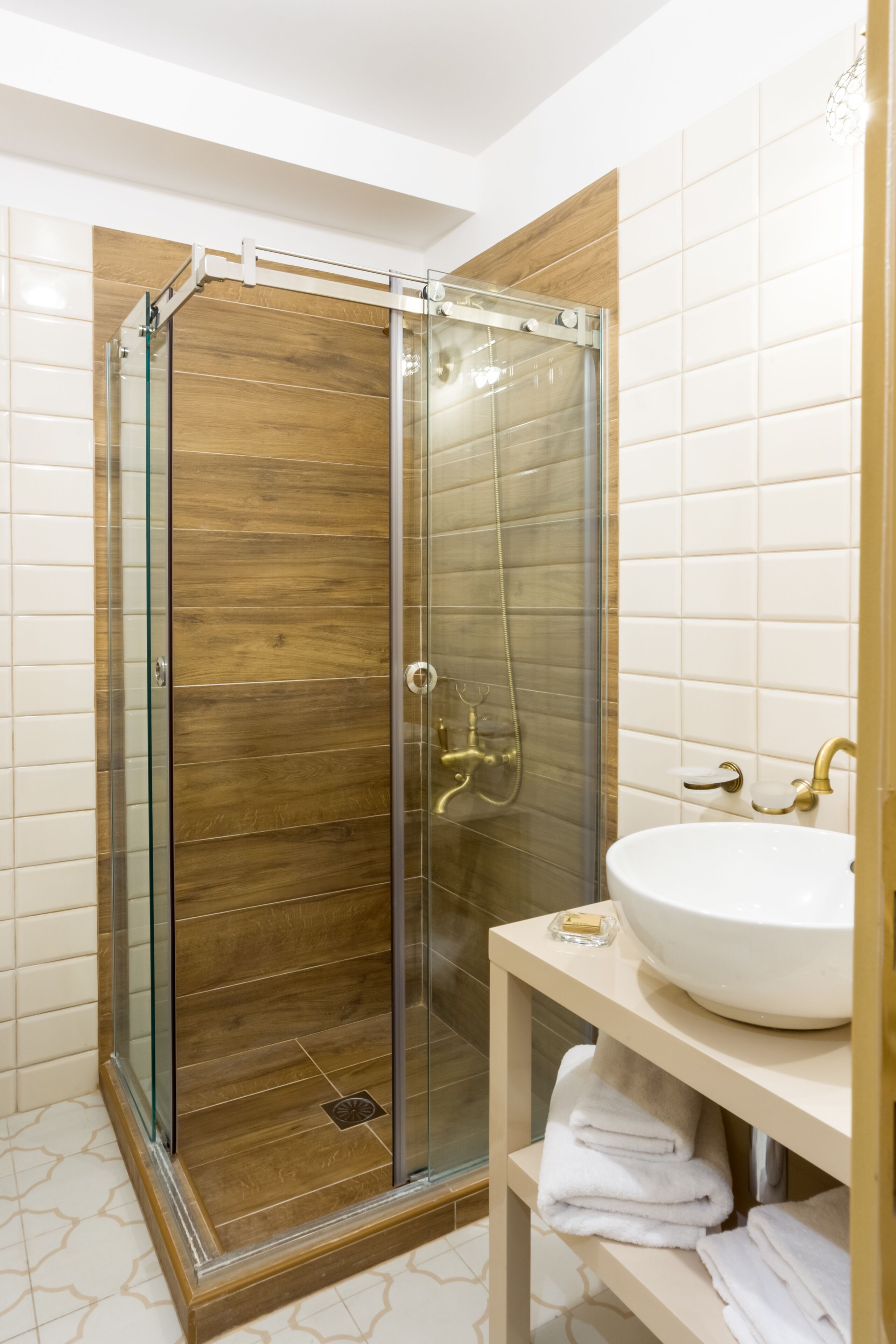 A modern bathroom with a glass-enclosed shower, a white sink, and neatly folded towels on a shelf.
