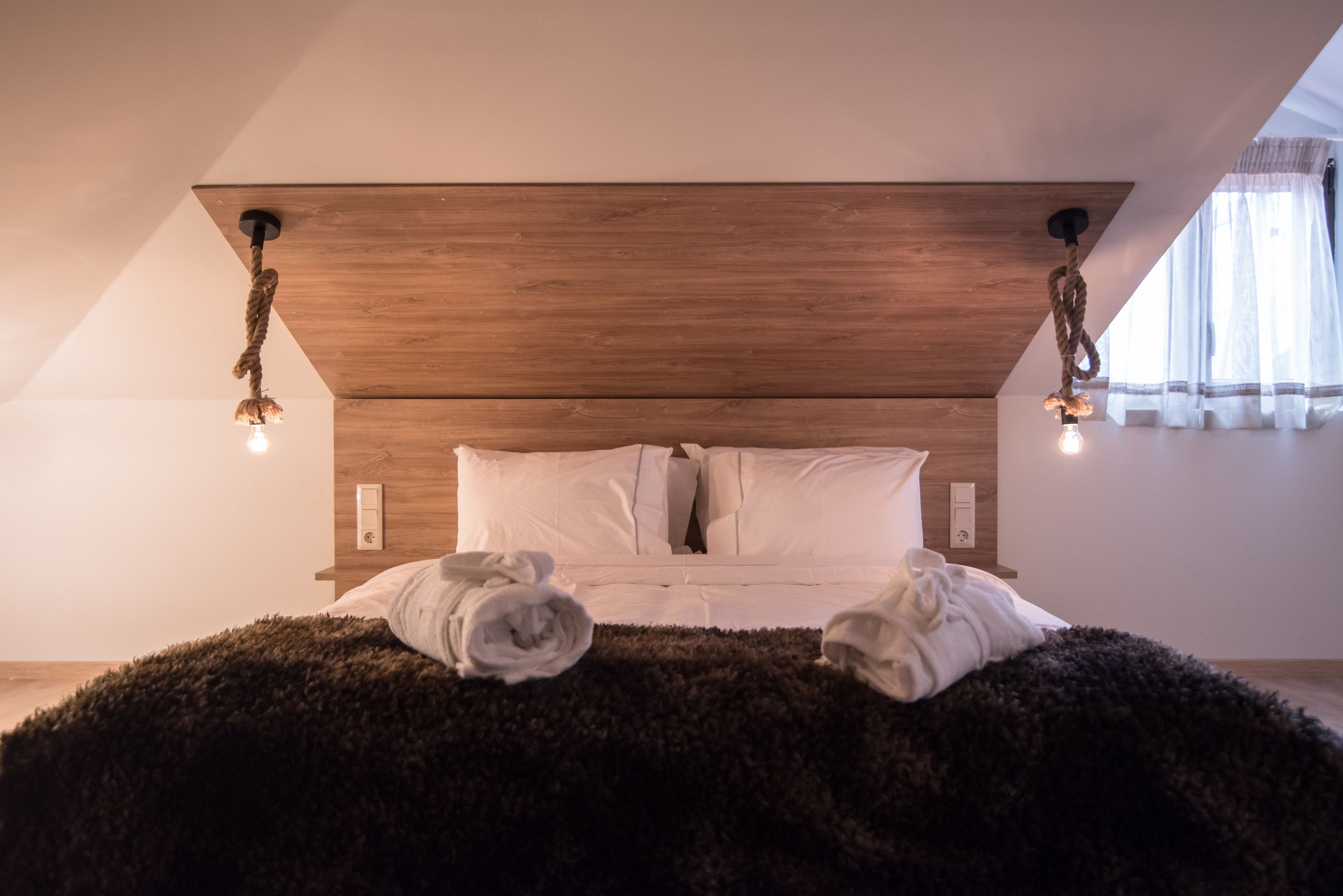 A bedroom with a wooden headboard, white bedding, and a fluffy rug.