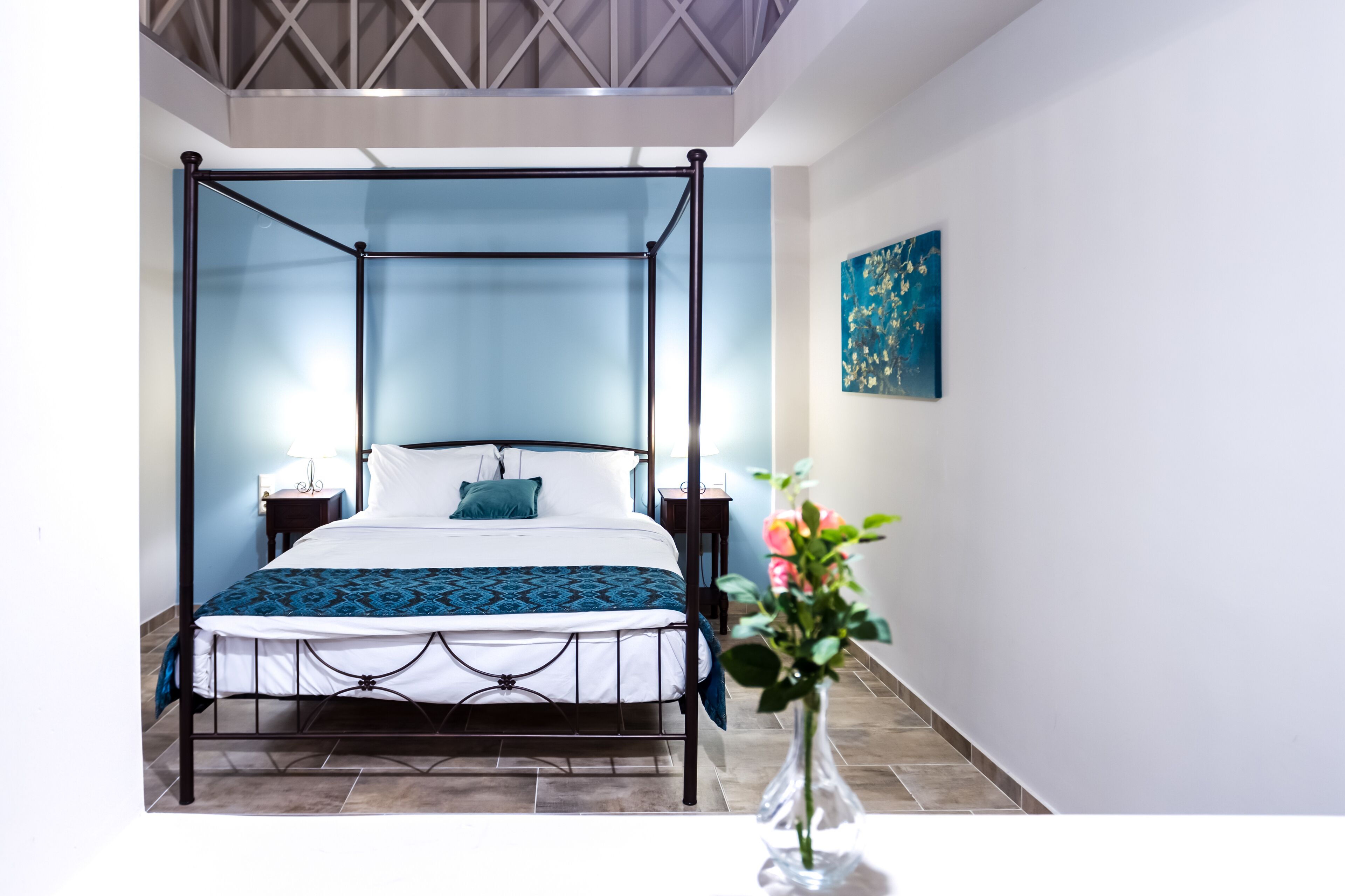 Una cama con dosel en una habitación con pared azul y un cuadro.