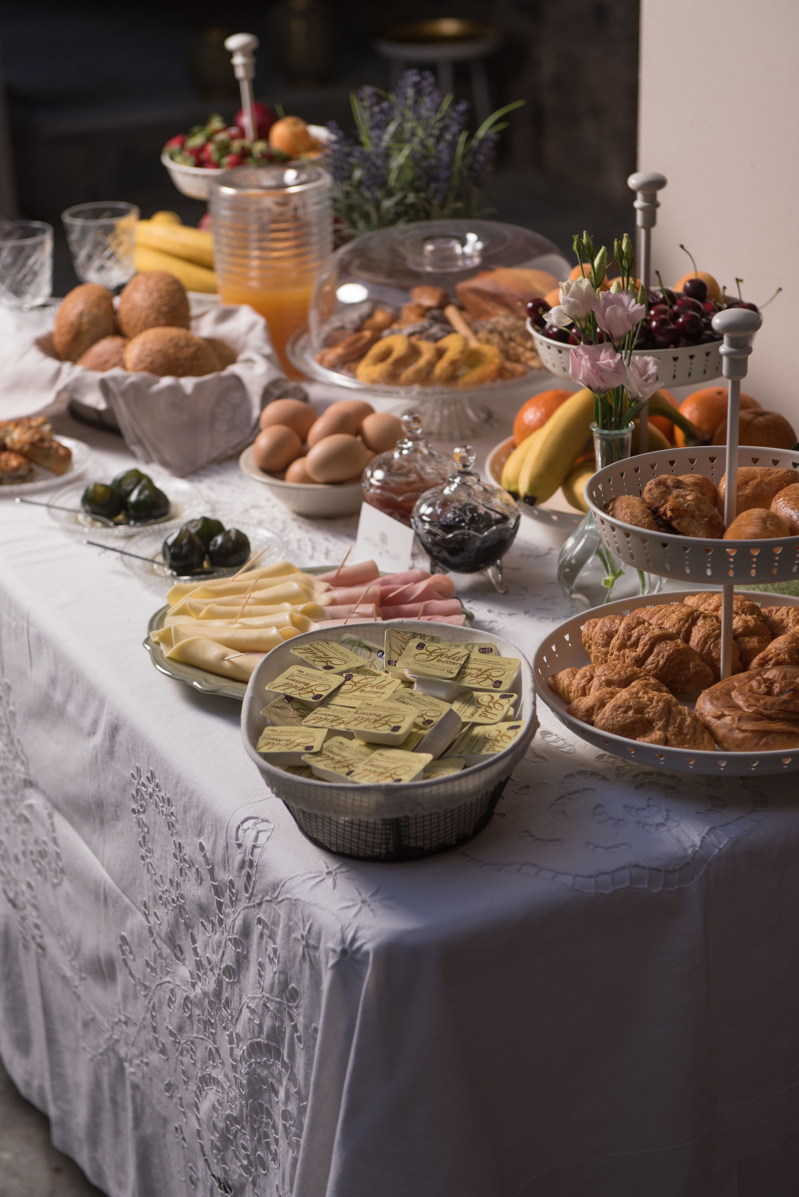 Une table de buffet proposant une variété d’aliments, notamment des pâtisseries, des fruits et des boissons.