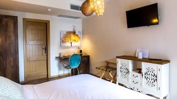Habitació d'hotel amb un llit, una taula de treball amb una cadira, una televisió i un armari.