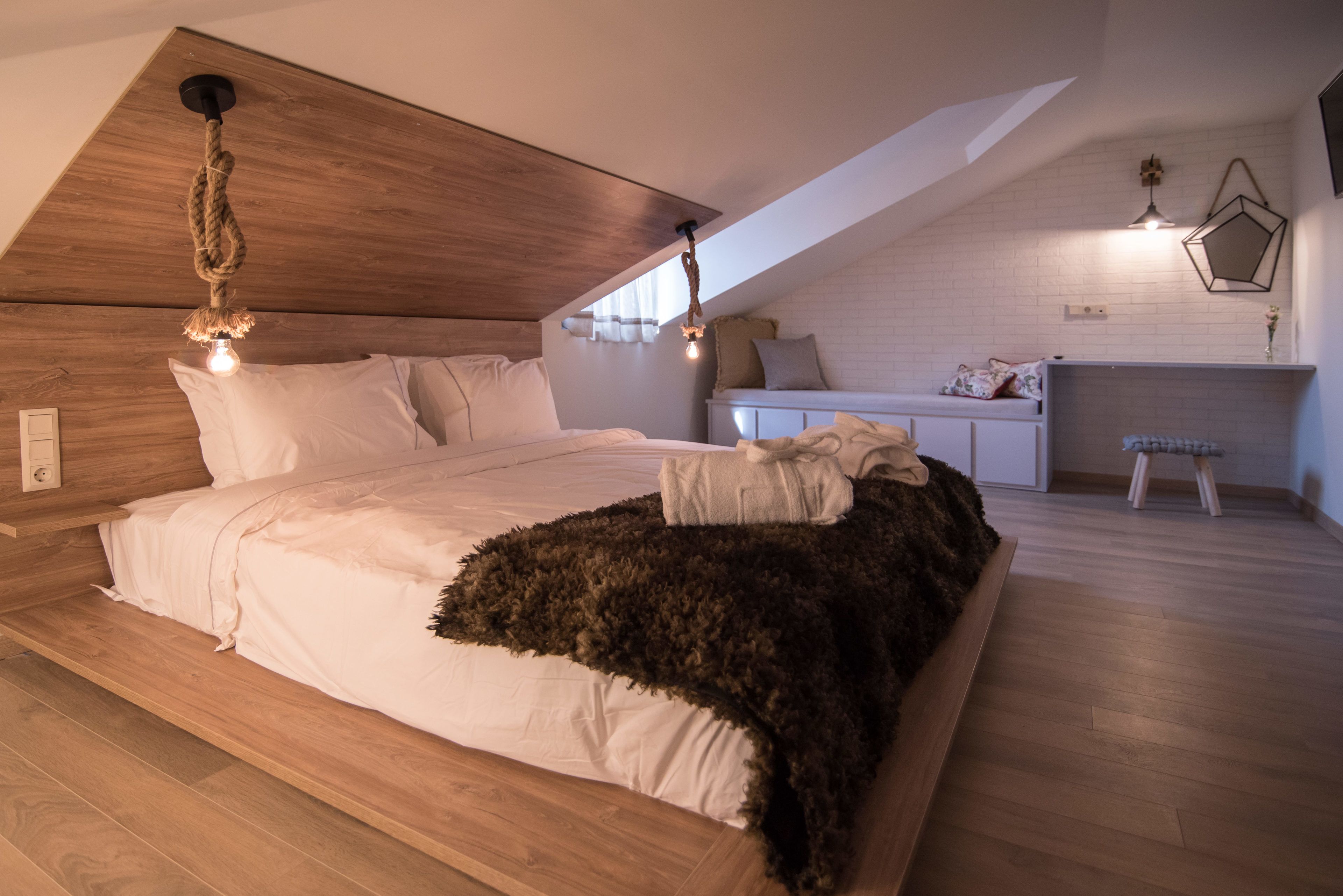 A bedroom with a large bed, wooden ceiling, and a small kitchenette area.