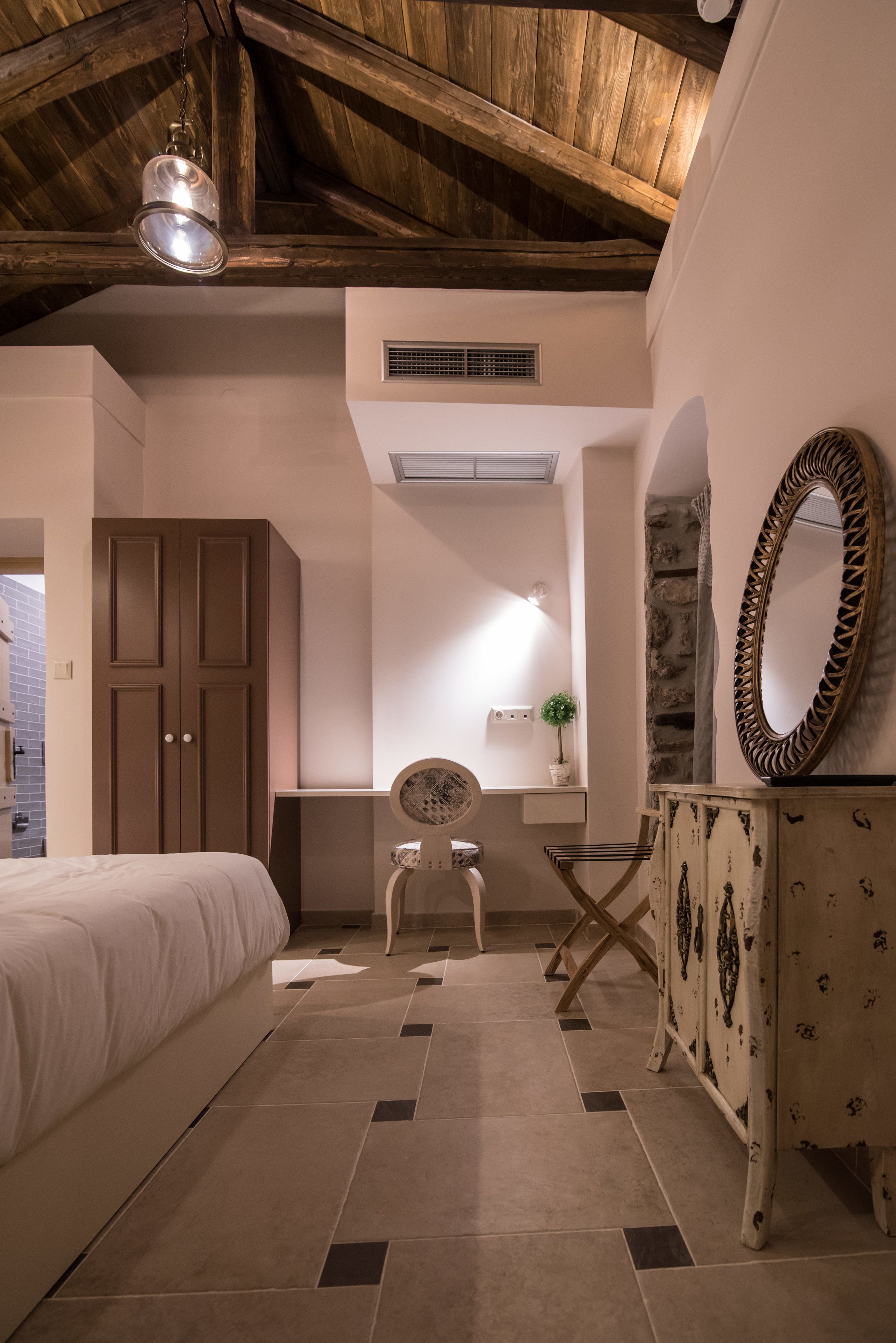 A bedroom with a bed, a dresser, a chair, and a mirror.