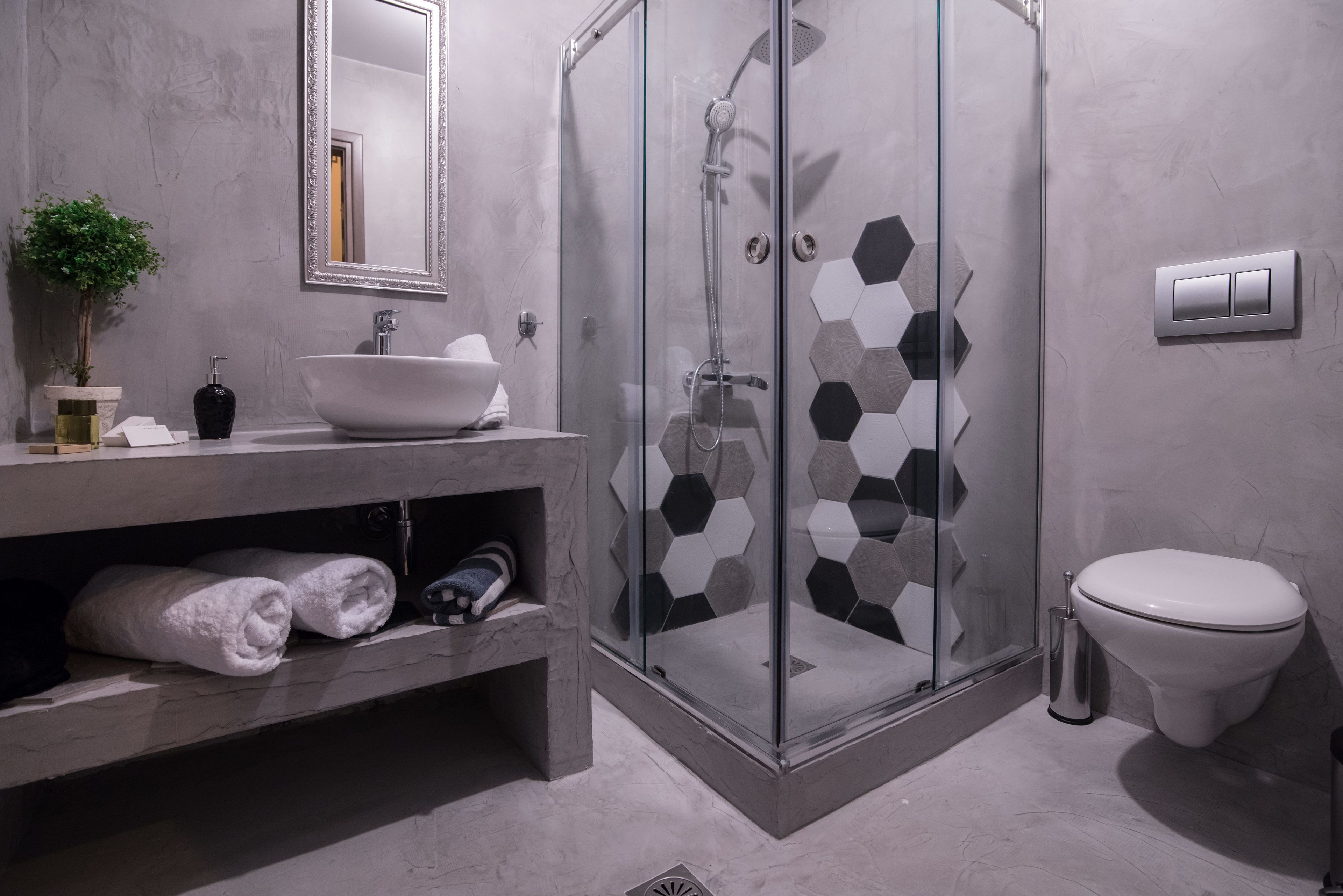 Un baño moderno con ducha de vidrio, lavamanos blanco y retrete.