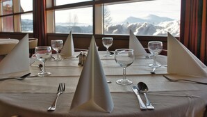 Une table dressée pour un repas, avec une vue sur les montagnes par la fenêtre.