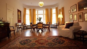 Un salón espacioso con zona de comedor, con muebles de madera, una alfombra grande y una araña.