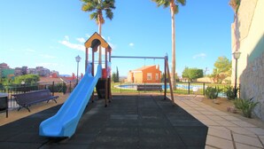 A playground with a blue slide, a swing set, and a bench. - Apartamento CasaTuris Bonalba Golf (Mutxamel)