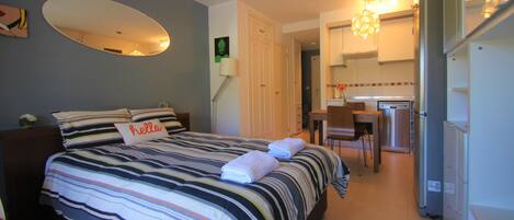 Una habitación de hotel con cama, escritorio y kitchenette.