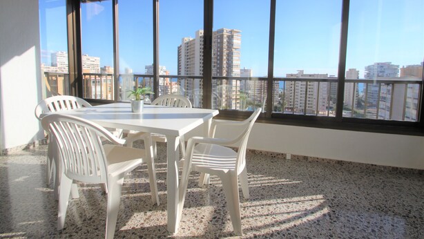 A room with a large window, a white table, and four white chairs. - Apartamento CasaTuris Portobello (Alicante)