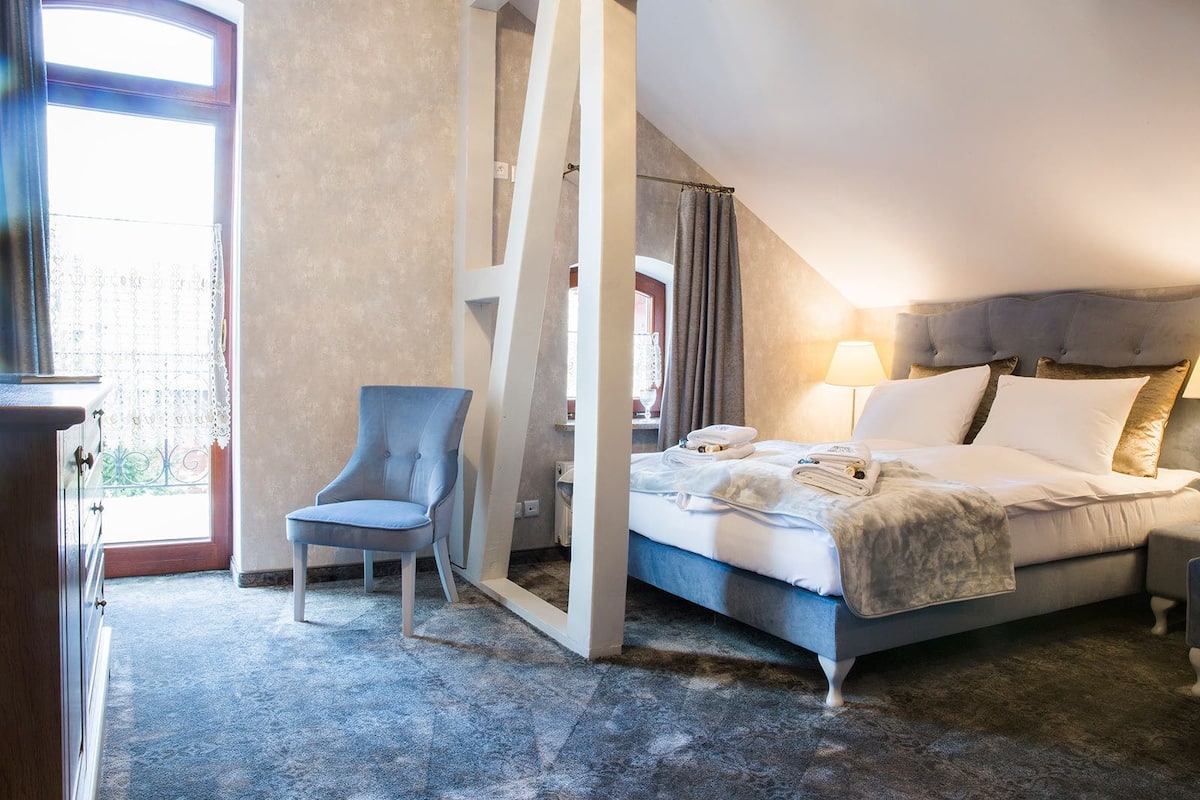 Habitación de hotel con cama, una silla y vistas al exterior.