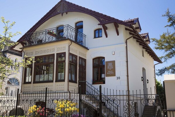 A two-story building with a balcony, a sign reading "Villa Mistral," and a number "10" on the facade.