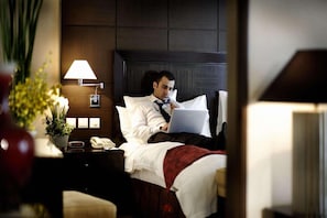 A hotel room with a bed, a bedside lamp, a telephone, and a laptop on the bed. - V Continent Parkview Wuzhou (Beijing)