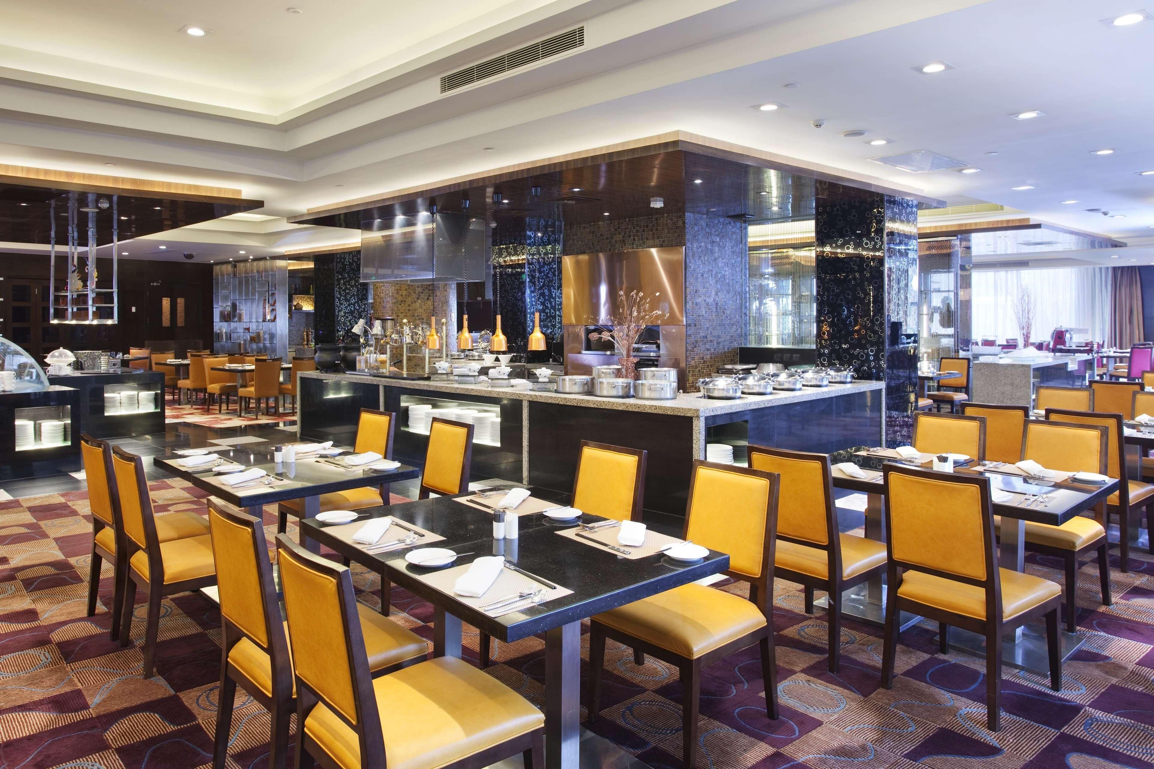 A hotel restaurant with multiple dining tables, chairs, and a central bar area.