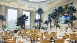 Um hall amplo com pé direito alto, grandes janelas e diversas áreas de estar.