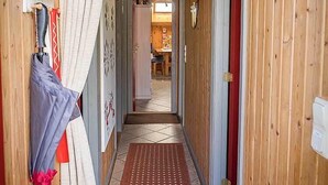 A narrow hallway with wooden walls, a tiled floor, and a red door at the end. - Juwel Feriendorf Glücksburg - Holnis 13 (Gluecksburg)