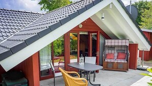 A house with a sloped roof, a patio with a table and chairs, and a covered outdoor seating area. - Juwel Feriendorf Glücksburg - Holnis 13 (Gluecksburg)