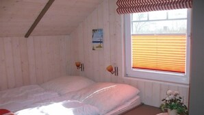 A single bed in a room with wooden walls and a window with blinds. - Juwel Feriendorf - Lille Blå Søster (Gluecksburg)