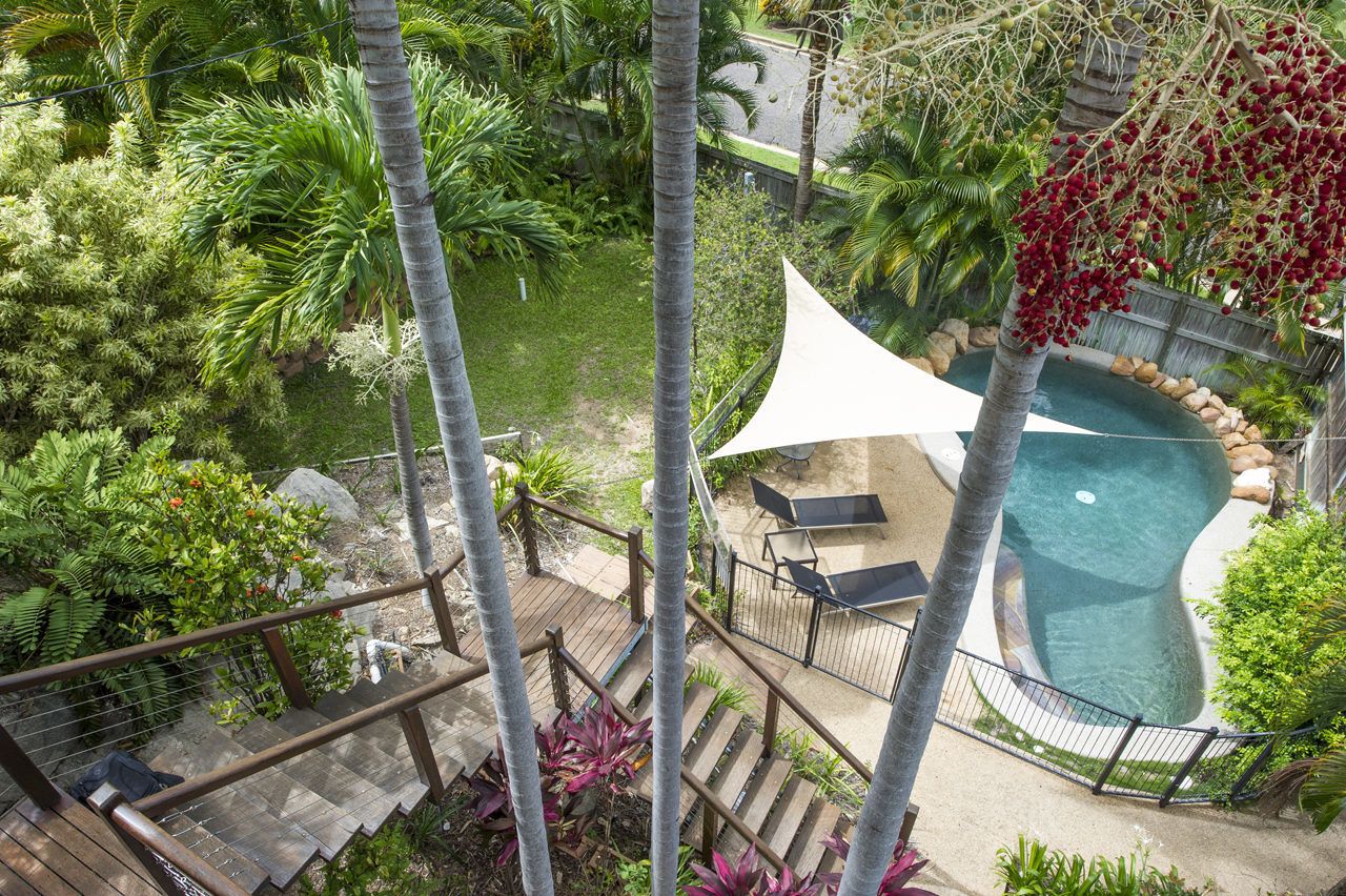 A pool area with a white canopy, surrounded by palm trees and lush greenery.