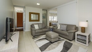 A modern living room with a sofa set, a TV, and a lamp. - 1 Bright Point Apartment 1503 (Nelly Bay)
