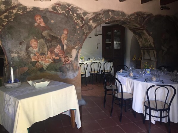 A dining area with tables set for a meal, a mural on the wall, and a rustic ceiling.