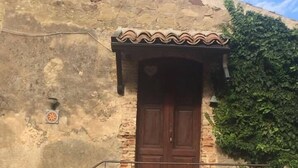 A rustic stone building with a wooden door, a small porch with a bench, and potted plants. - Villa Nicetta (San Fratello)