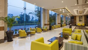 A spacious lobby with yellow seating, large windows, and a view of a road and greenery. - Lemon Tree Hotel, Sector 68, Sohna Road, Gurugram (Gurugram)