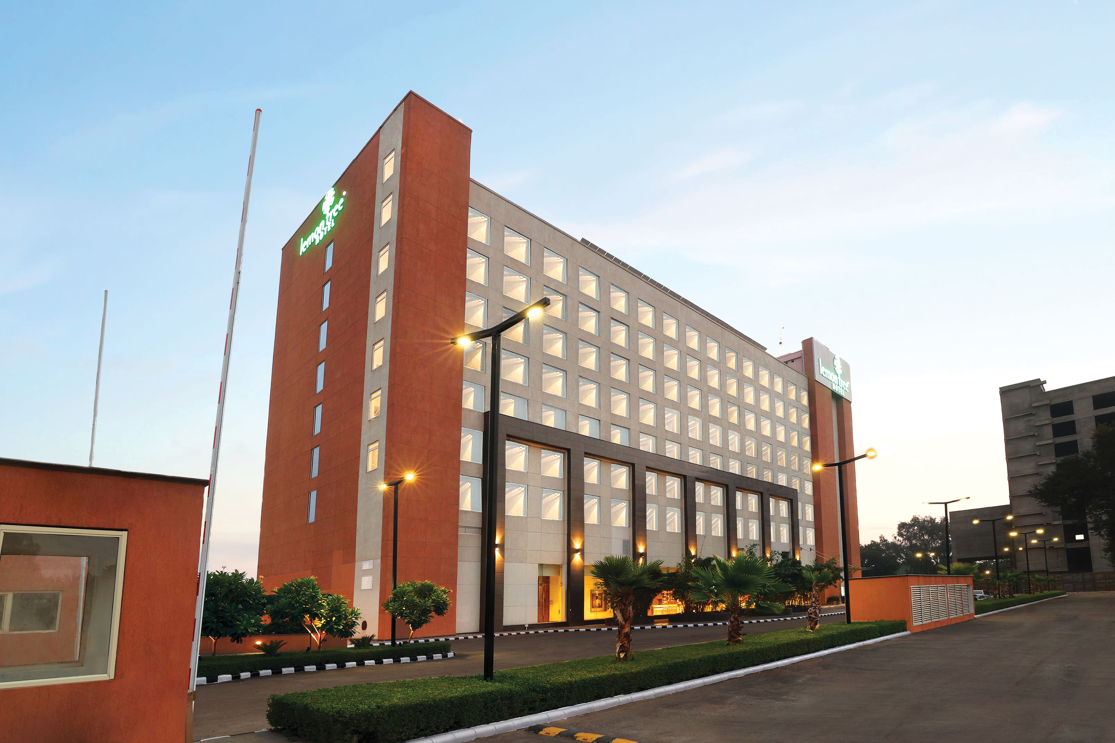 A modern hotel with a prominent entrance, multiple floors, and a well-maintained garden area.