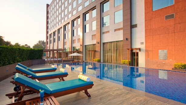 A hotel with a rooftop pool, lounge chairs, and a modern building facade. - Lemon Tree Hotel, Sector 68, Sohna Road, Gurugram (Gurugram)
